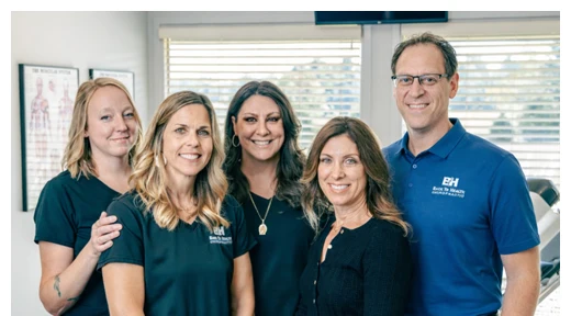 Matthew Kirkham and His Team Pose in Front of the Entrance Window of Back To Healthcare Chiropractic
