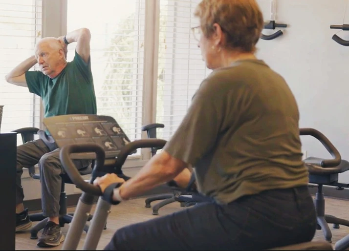 Posture Rehab Center Woman on Sitting Bicycle and Man Stretching